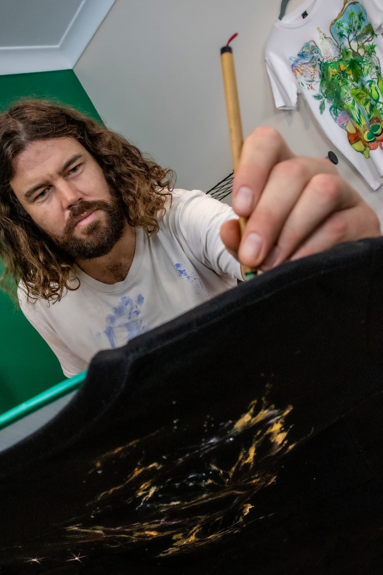 Sebastian concentrating on a brushstroke with a Galaxy shirt in the foreground.