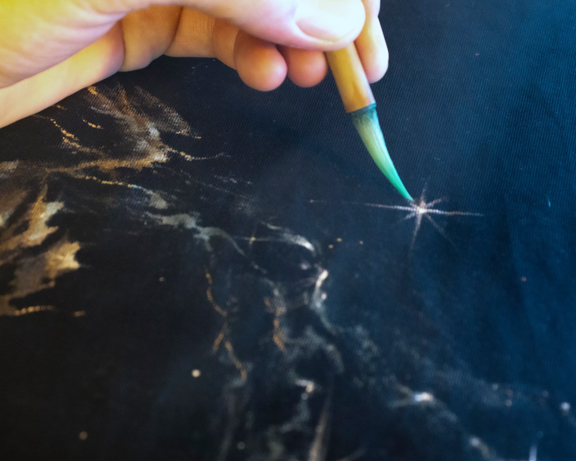 A fine brush touching the centre of a white star on a Galaxy shirt.
