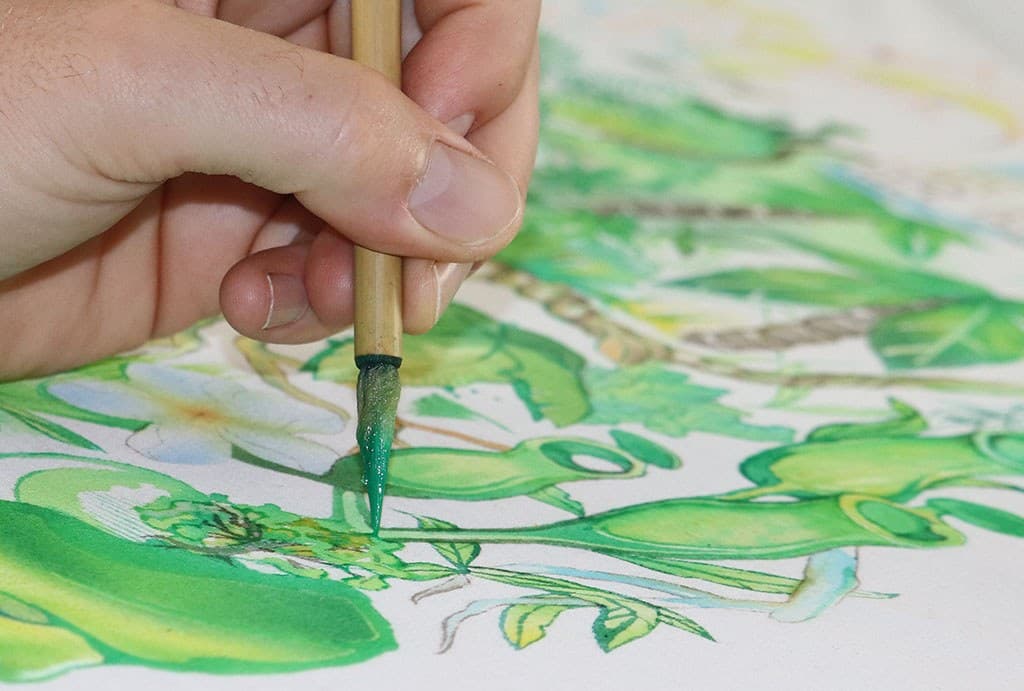 A fine brush adding green details to a Jungle shirt by hand.